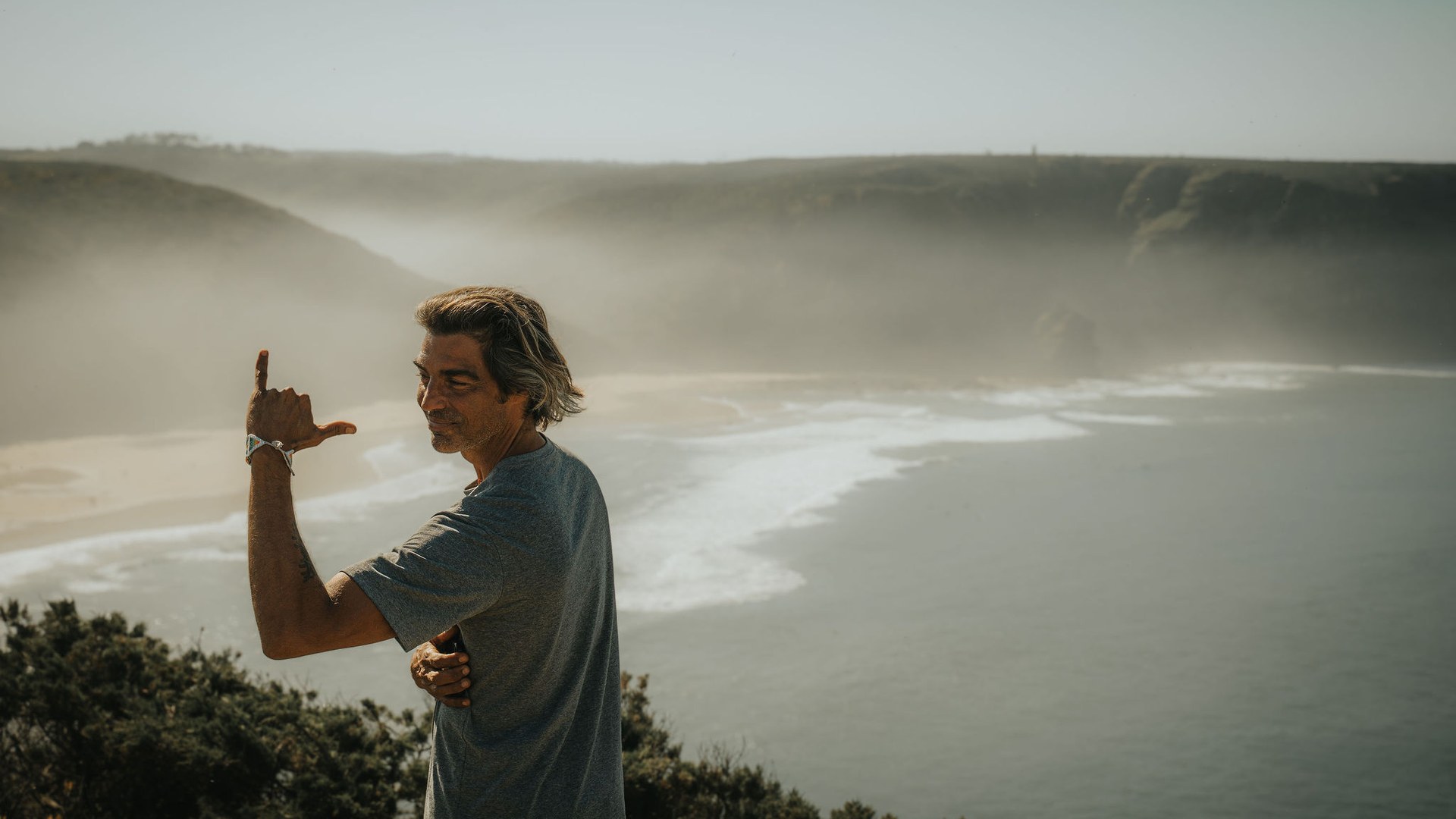 A man on the cliffs of the Costa Vicentina, mist over the beach and the Atlantic