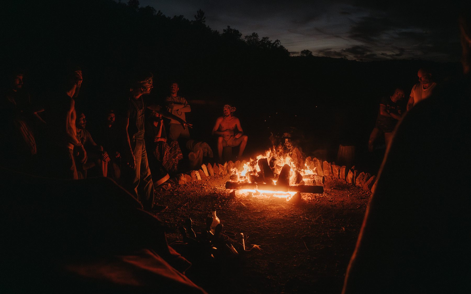Men in circle around the fire at a Men's Academy intensive on the land
